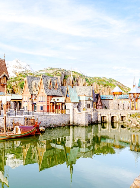 Arendelle village and castle at Disneyland World of Frozen, with a boat on the water.
