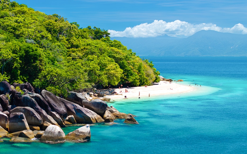 Fitzroy Island beach with clear water and lush greenery, Cairns day trip.