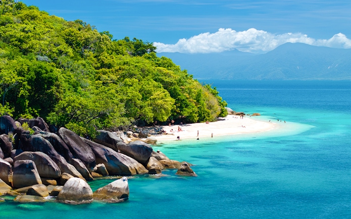 Fitzroy Island beach with clear water and lush greenery, Cairns day trip.