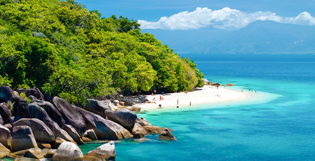 Snorkelers exploring coral reefs near Fitzroy Island, visible from a glass-bottom boat on a Cairns day trip.