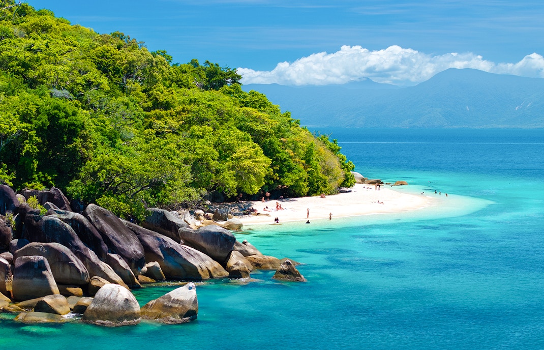 Fitzroy Island beach with clear water and lush greenery, Cairns day trip.