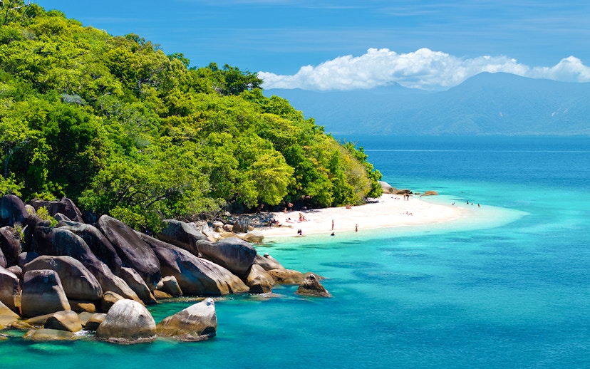 Fitzroy Island beach with clear water and lush greenery, Cairns day trip.