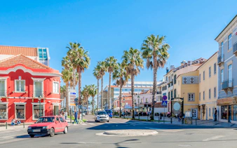 Street view with palm trees and colorful buildings in Cascais, Portugal.