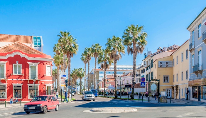 Street view with palm trees and colorful buildings in Cascais, Portugal.