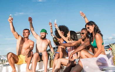 Group of friends toasting with champagne on a yacht under a sunny sky.