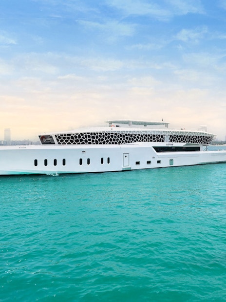 Lotus Mega Yacht cruising near Dubai Marina with city skyline in the background.