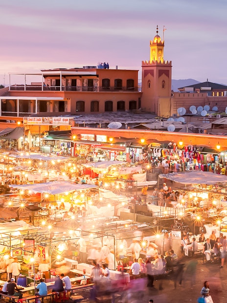Marrakech night market bustling with people and food stalls under vibrant lights.
