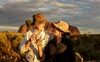 Couple toasting with wine at sunset near Uluru on a full-day tour from Alice Springs.