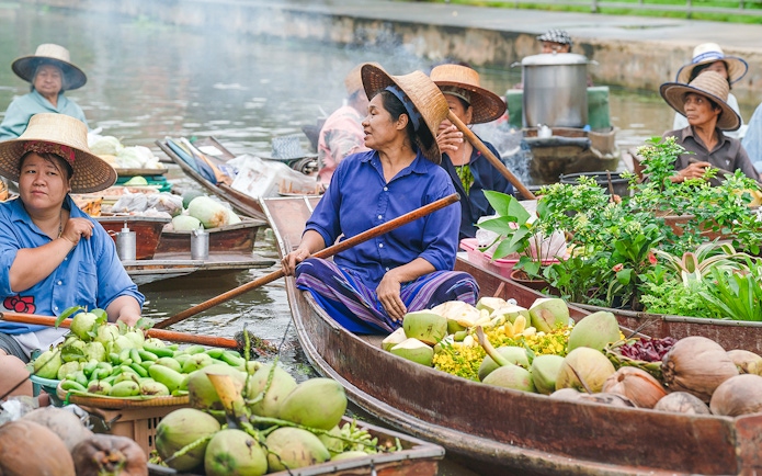Vendors selling fruits and vegetables on boats at Damnoen Saduak Floating Market, Bangkok.