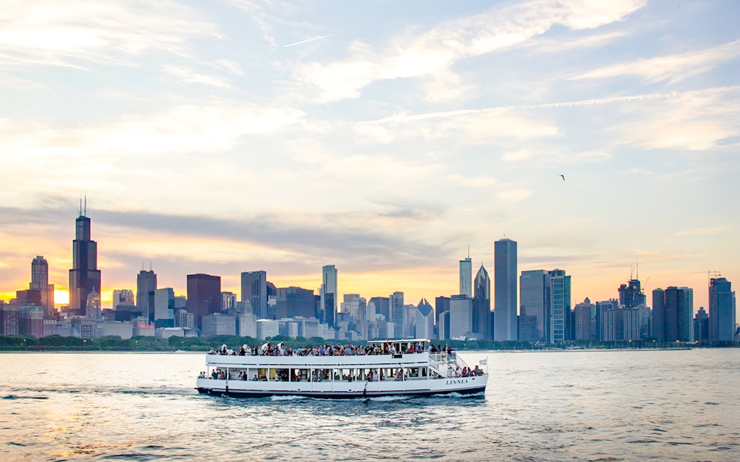 Cruise boat on Lake Michigan with Chicago skyline at sunset.