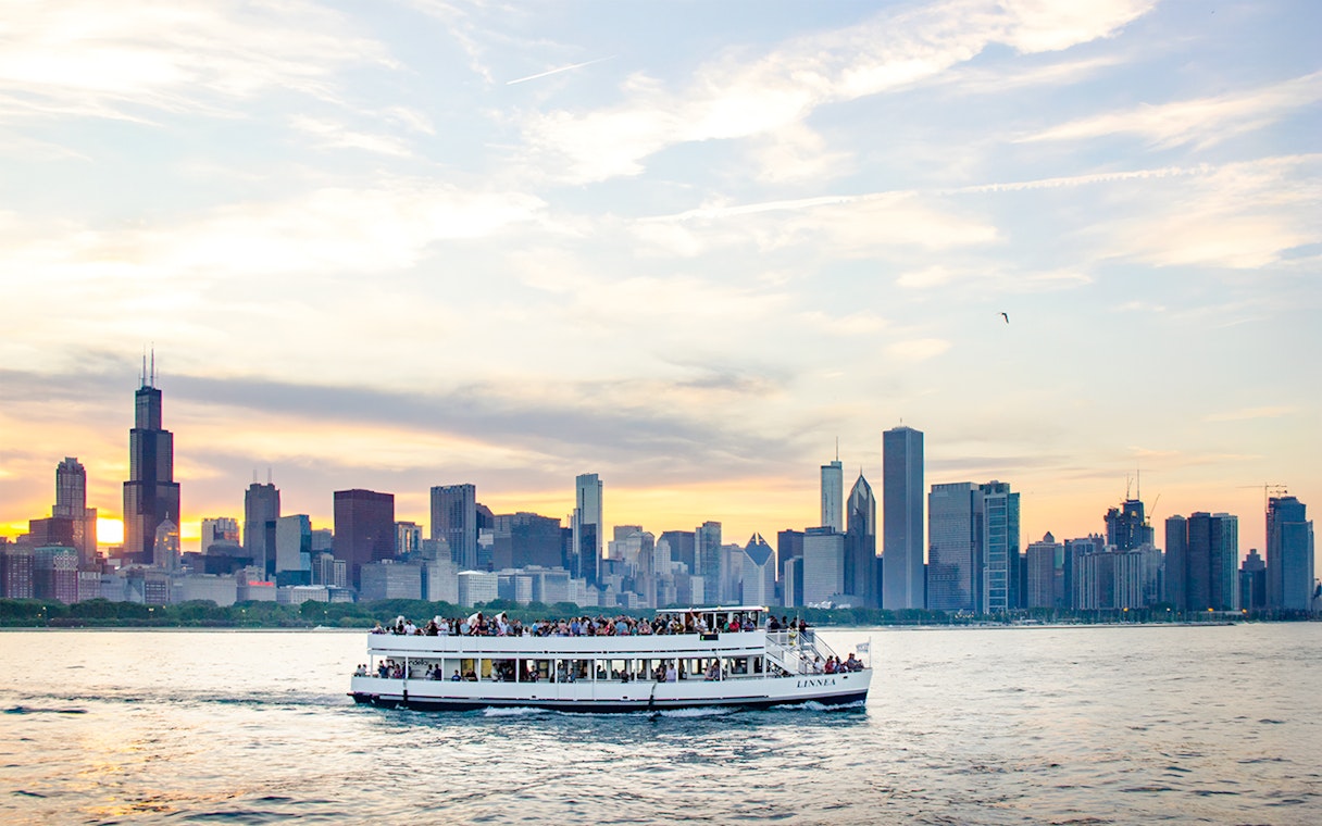 Cruise boat on Lake Michigan with Chicago skyline at sunset.