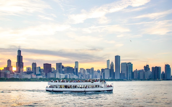Cruise boat on Lake Michigan with Chicago skyline at sunset.