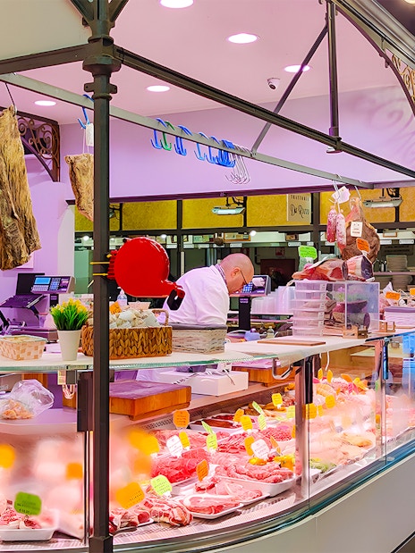 Florence meat shop with cured meats and butchers preparing orders.