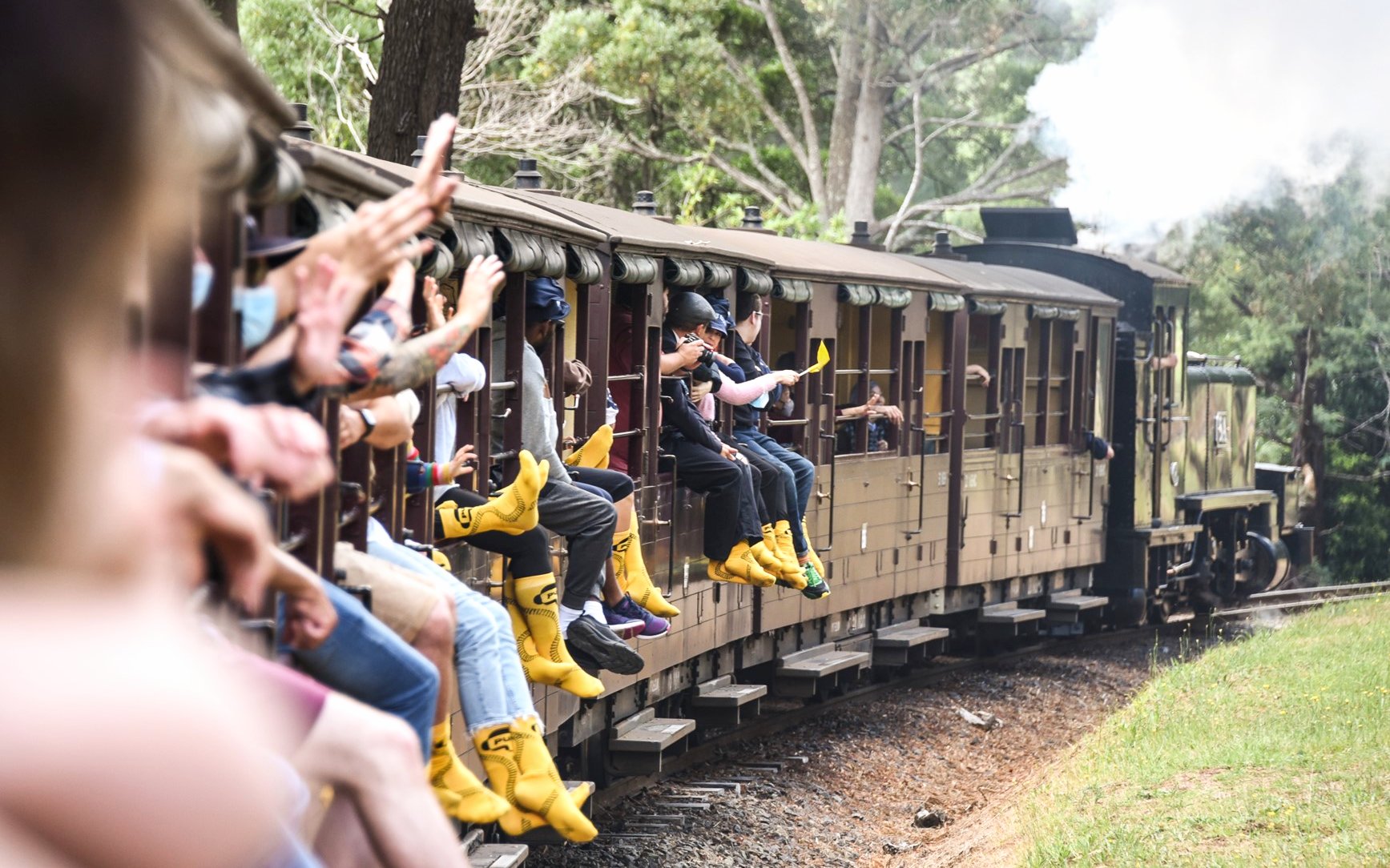 Passengers on Puffing Billy Steam Train with legs hanging out, Melbourne.