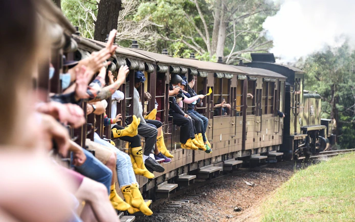 Passengers on Puffing Billy Steam Train with legs hanging out, Melbourne.