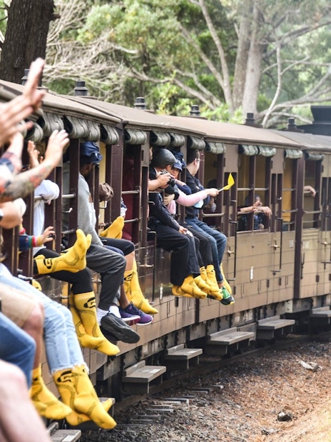 Passengers on Puffing Billy Steam Train with legs hanging out, Melbourne.