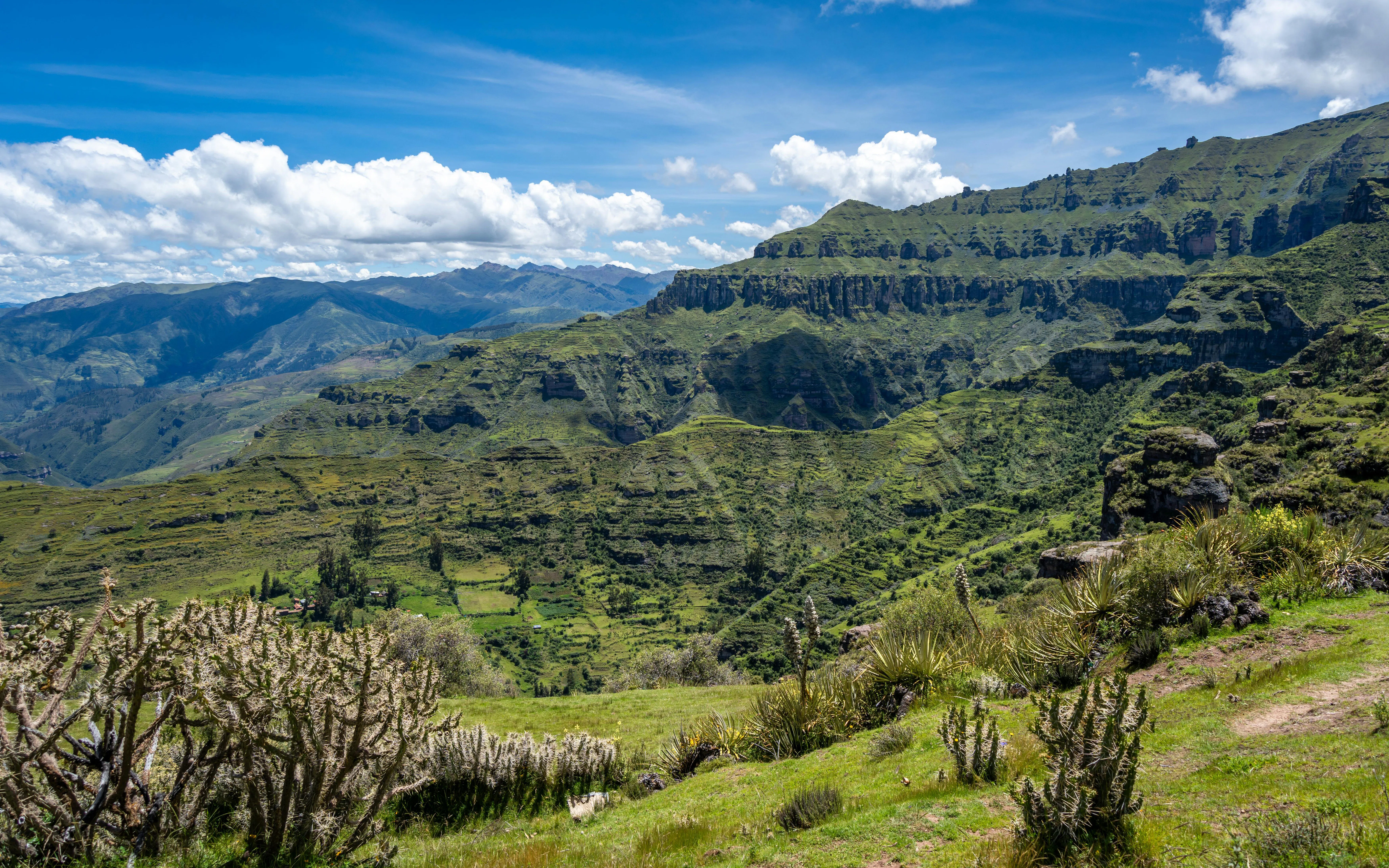 Rock formations and green valleys in the Andean Mountains at Waqrapukara, Peru.