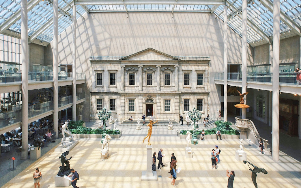 Grand interior court of the Metropolitan Museum of Art, New York City, with sculptures and visitors.