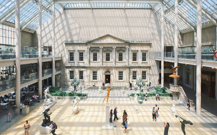 Grand interior court of the Metropolitan Museum of Art, New York City, with sculptures and visitors.