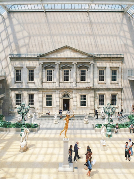 Grand interior court of the Metropolitan Museum of Art, New York City, with sculptures and visitors.