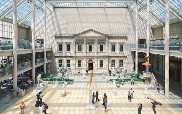 Grand interior court of the Metropolitan Museum of Art, New York City, with sculptures and visitors.