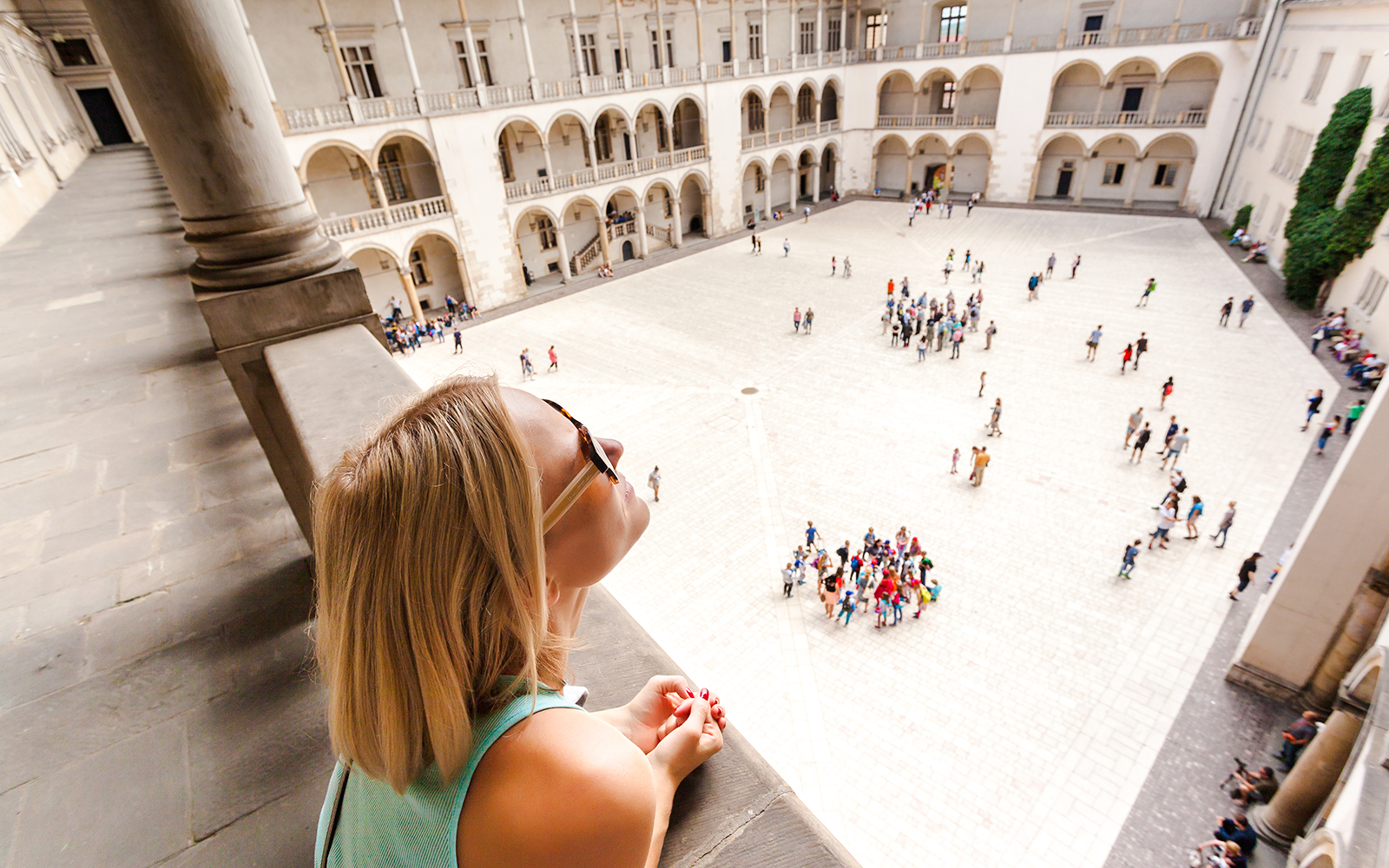 Visitor overlooking courtyard and arcades at Wawel Castle, Krakow.