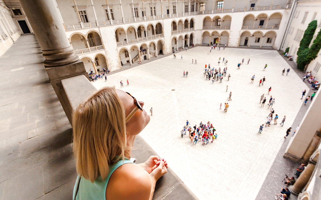 Visitor overlooking courtyard and arcades at Wawel Castle, Krakow.