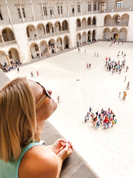 Visitor overlooking courtyard and arcades at Wawel Castle, Krakow.