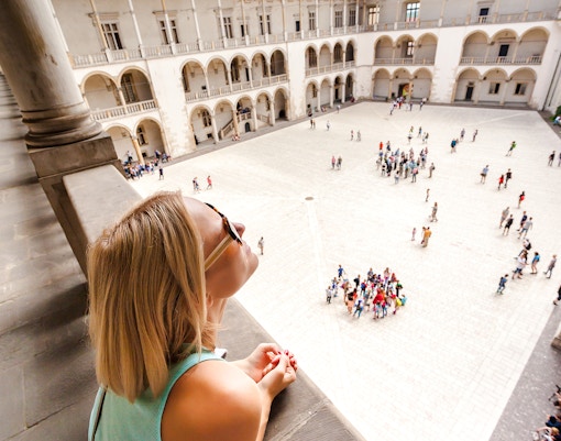 Visitor overlooking courtyard and arcades at Wawel Castle, Krakow.