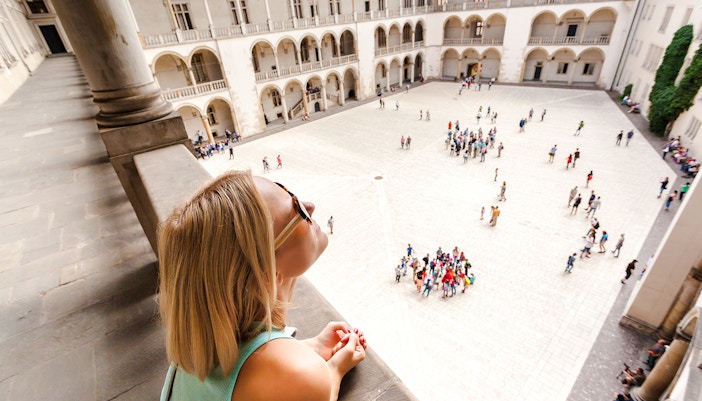 Visitor overlooking courtyard and arcades at Wawel Castle, Krakow.