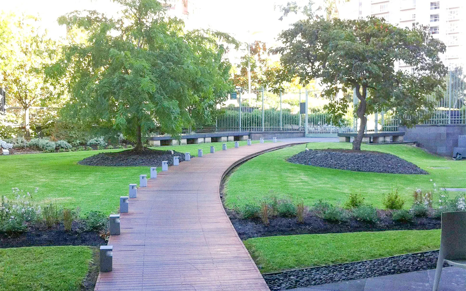 Curved pathway through NGV garden with trees and manicured lawns.