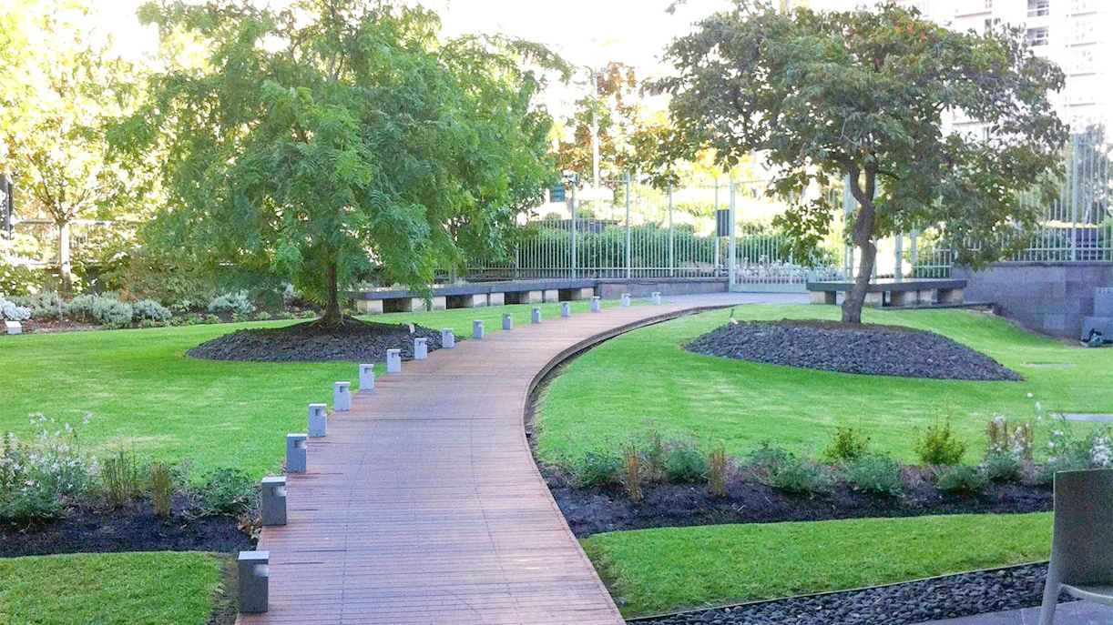 Curved pathway through NGV garden with trees and manicured lawns.