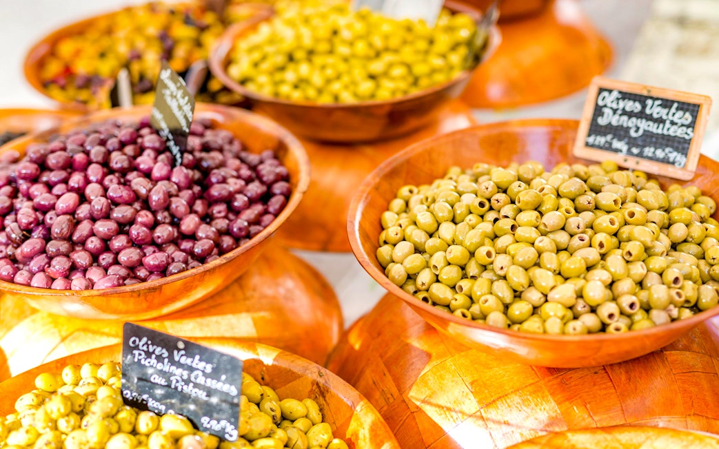 Bowls of green and purple olives at a Provencal market during a wine tasting sightseeing tour.