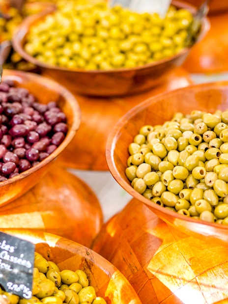 Bowls of green and purple olives at a Provencal market during a wine tasting sightseeing tour.