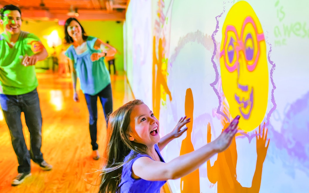 Children interacting with colorful wall projections at Crayola Experience in Orlando.