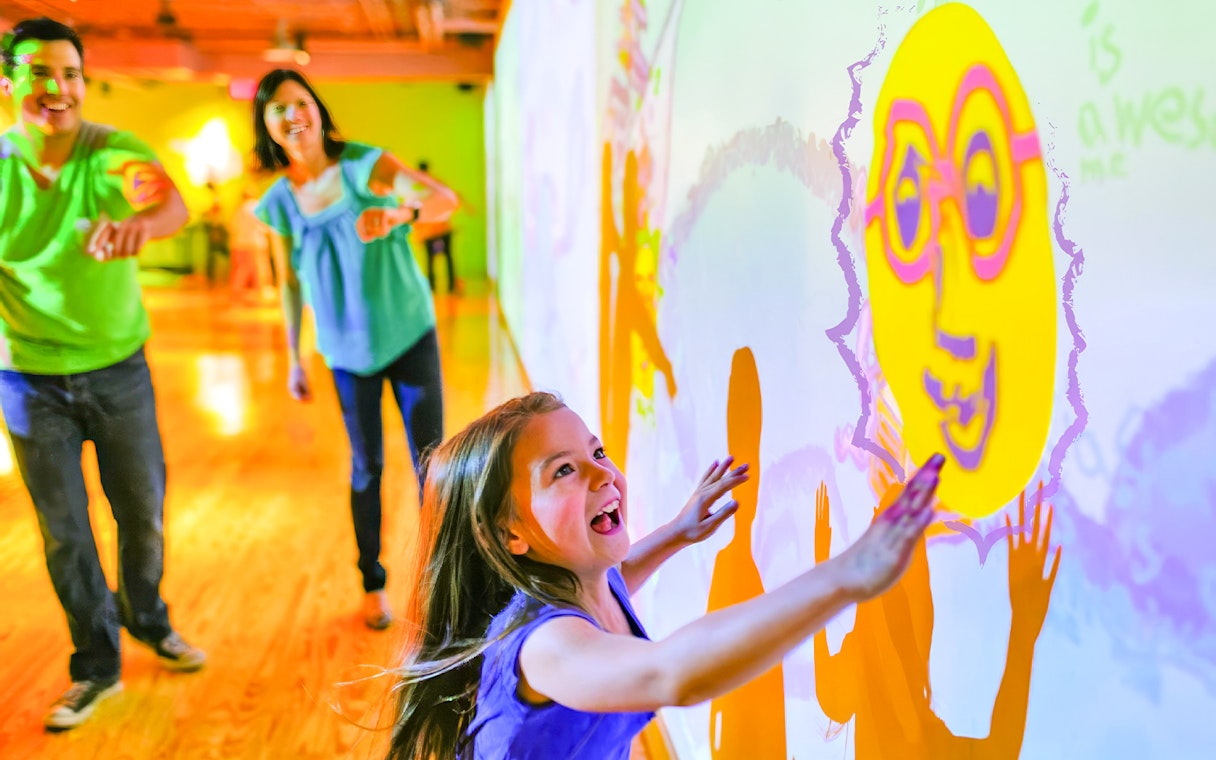 Children interacting with colorful wall projections at Crayola Experience in Orlando.