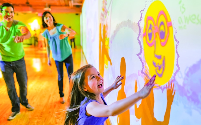 Children interacting with colorful wall projections at Crayola Experience in Orlando.