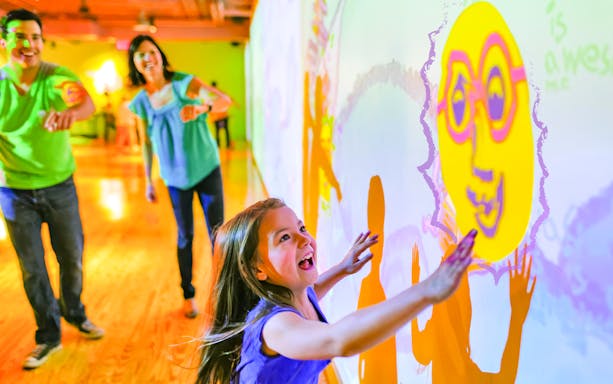 Children interacting with colorful wall projections at Crayola Experience in Orlando.