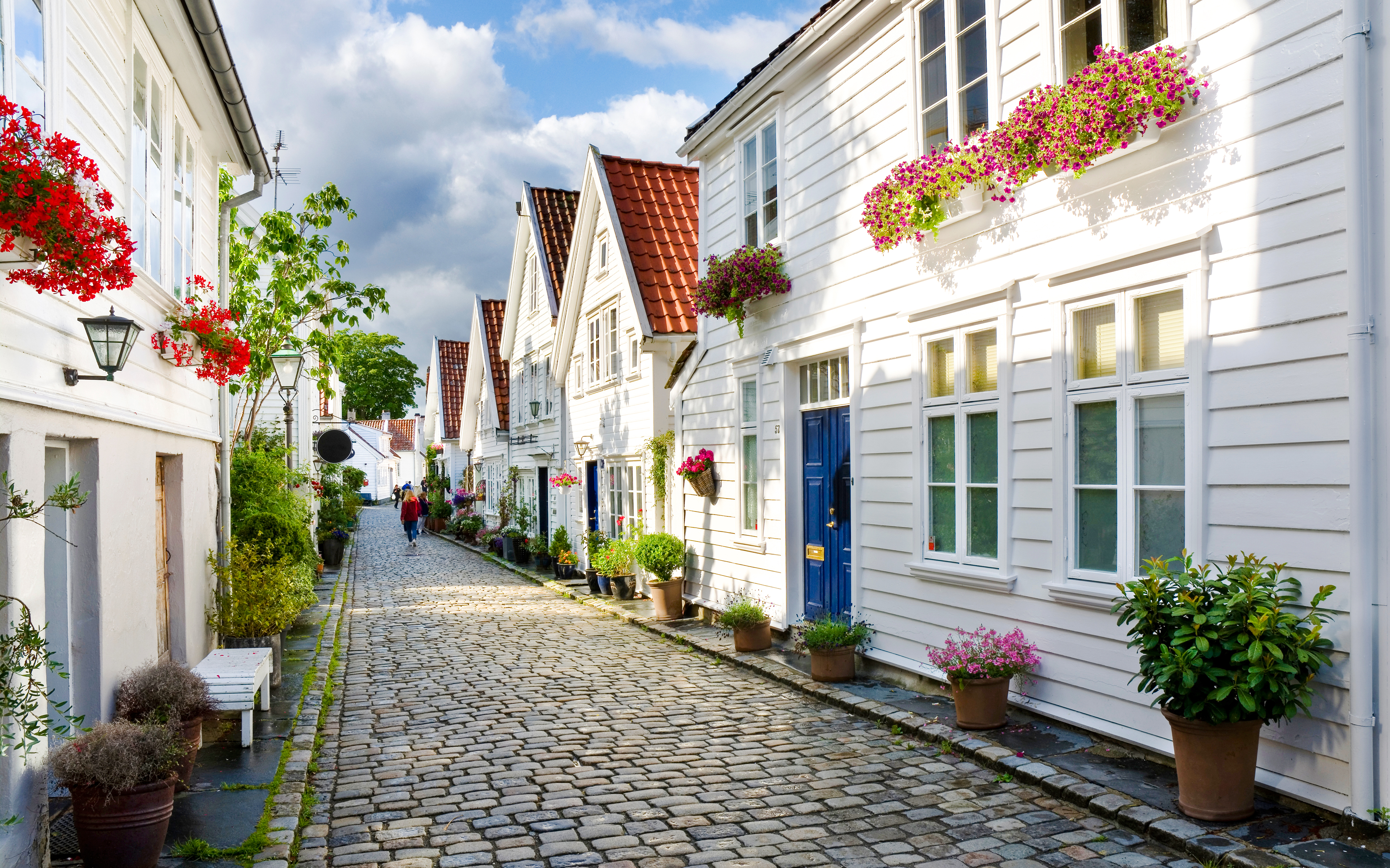 Cobblestone street with white wooden houses and flower pots in Stavanger, Norway.