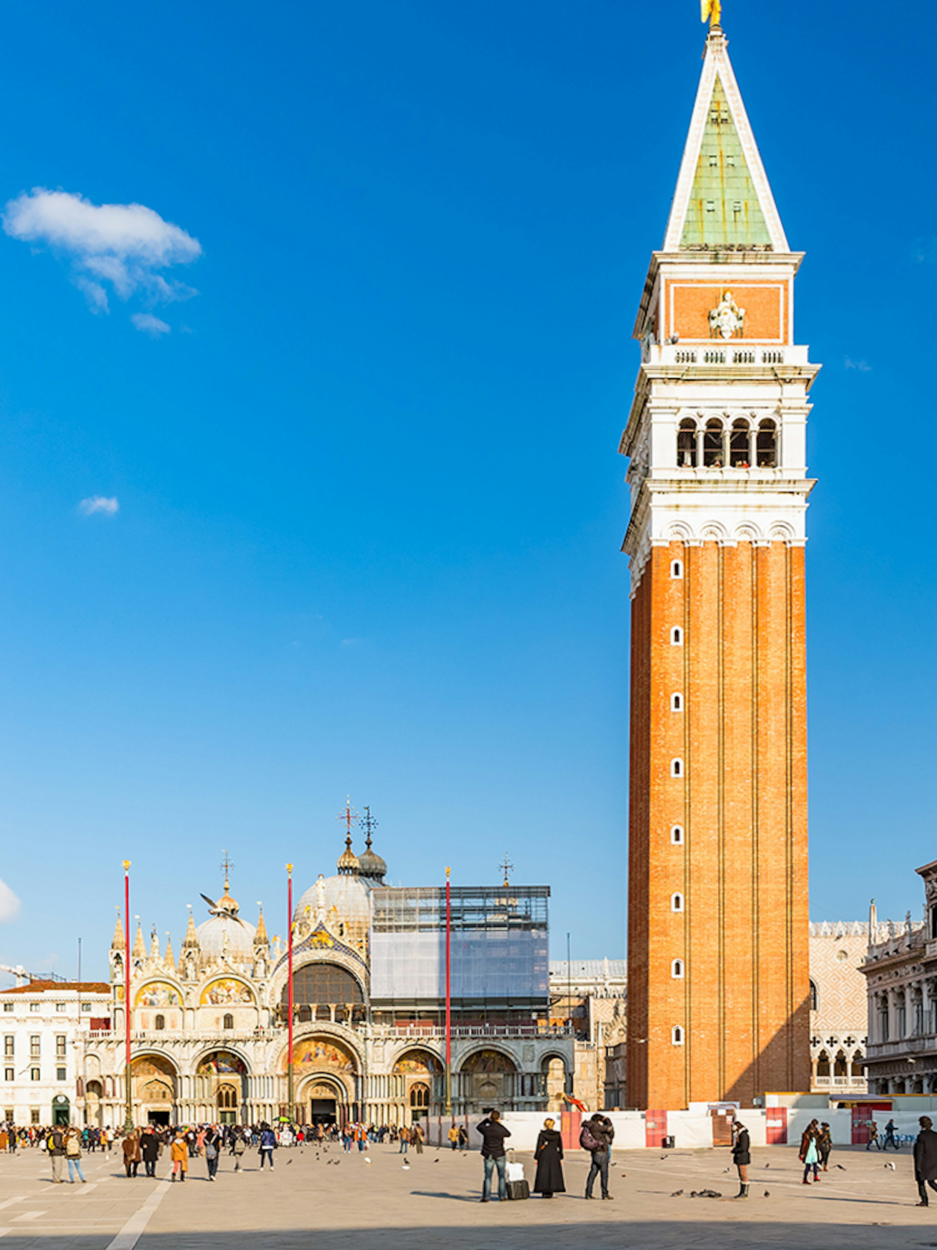 St. Mark's Basilica and Campanile in Venice, Italy, with tourists in the square.