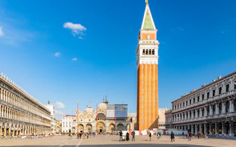 St. Mark's Basilica and Campanile in Venice, Italy, with tourists in the square.