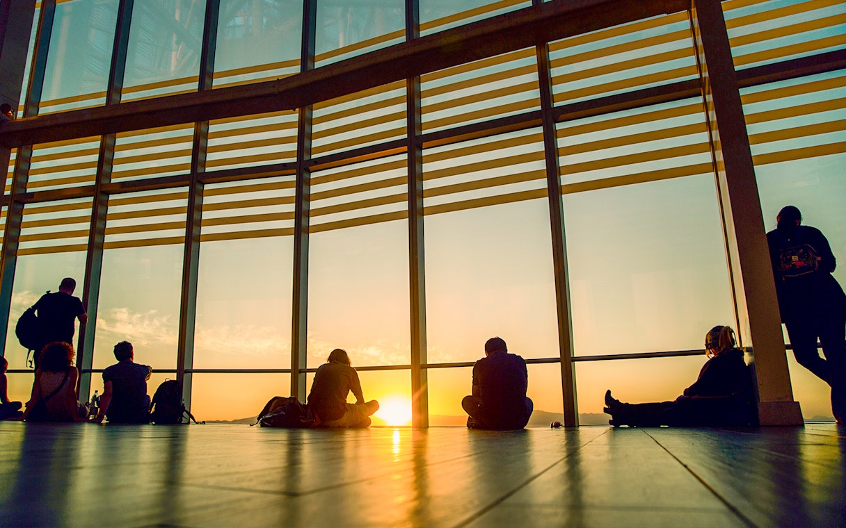 Sunset view from Sky Costanera, Chile, with people silhouetted against large windows.