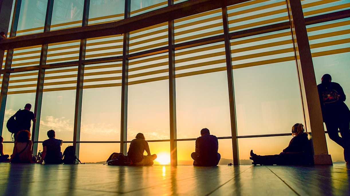 Sunset view from Sky Costanera, Chile, with people silhouetted against large windows.