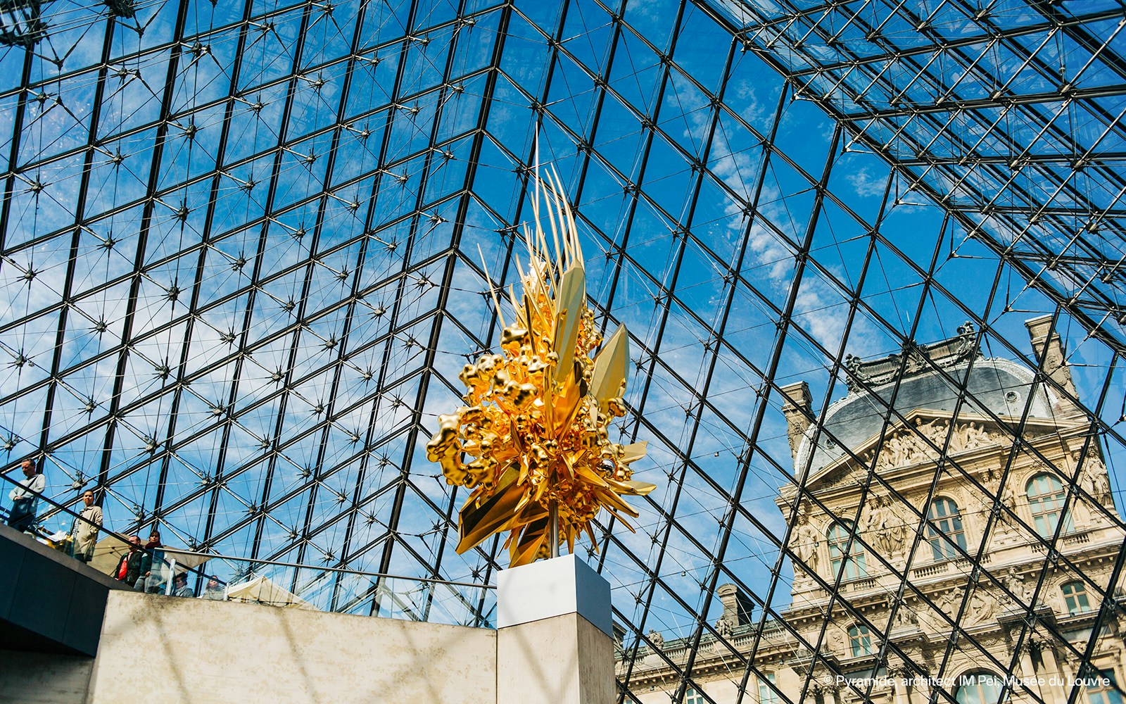 Golden art piece displayed under the Louvre Pyramid in Paris.