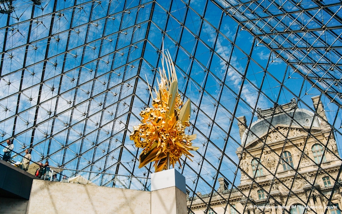 Louvre Museum glass pyramid interior with golden sculpture.