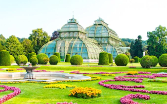 Palm House at Schönbrunn Palace, Vienna, surrounded by vibrant gardens.