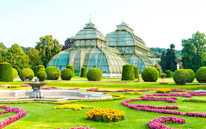 Palm House at Schönbrunn Palace, Vienna, surrounded by vibrant gardens.
