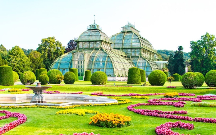 Palm House at Schönbrunn Palace, Vienna, surrounded by vibrant gardens.