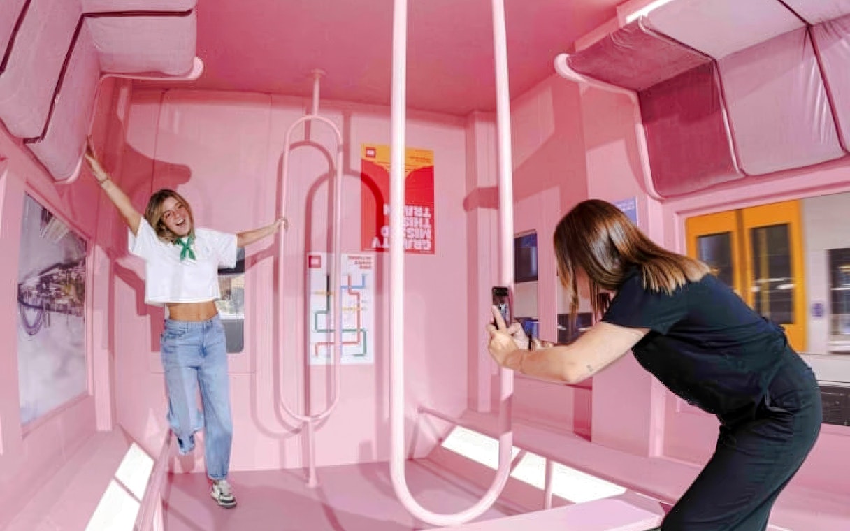 Person posing in a pink room with optical illusions at Mind Games - Art Alive! exhibit.