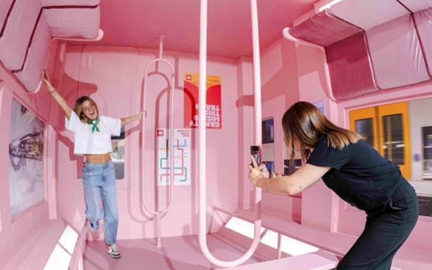 Person posing in a pink room with optical illusions at Mind Games - Art Alive! exhibit.